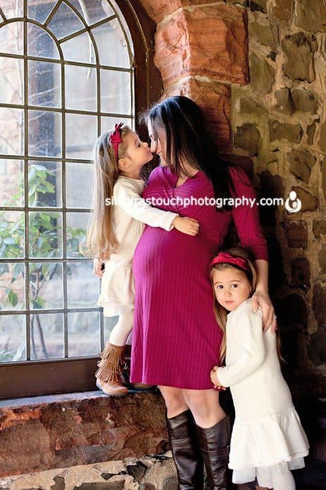 pregnant mom and her twin girls snuggled