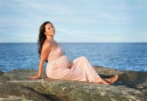 martenity mom photo laying on beach rocks