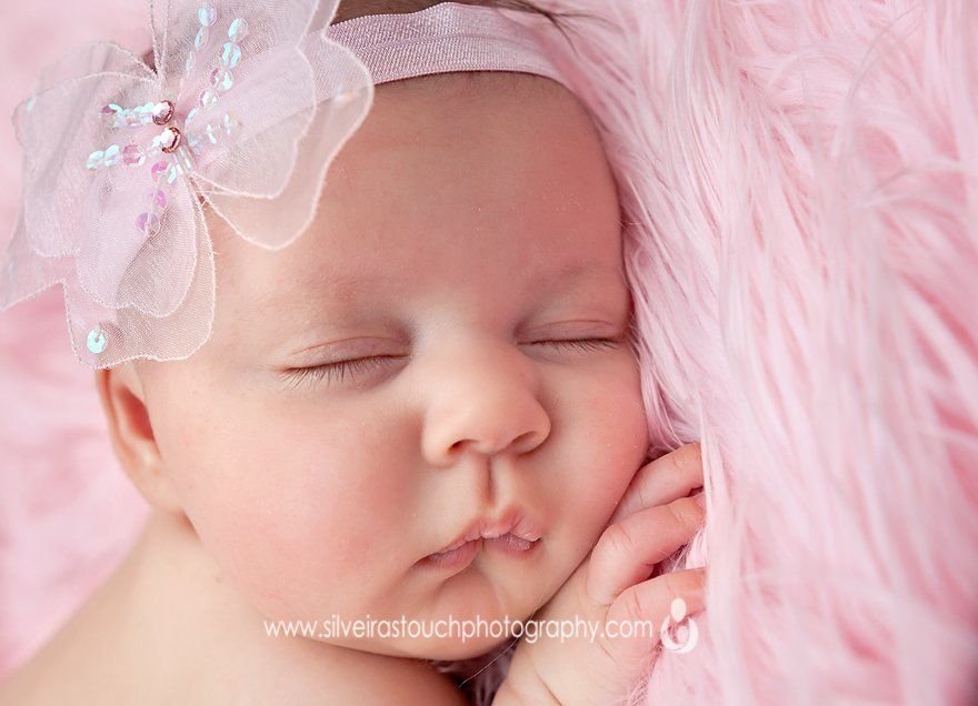 newborn girl wearing pink headband photographed on pink fur