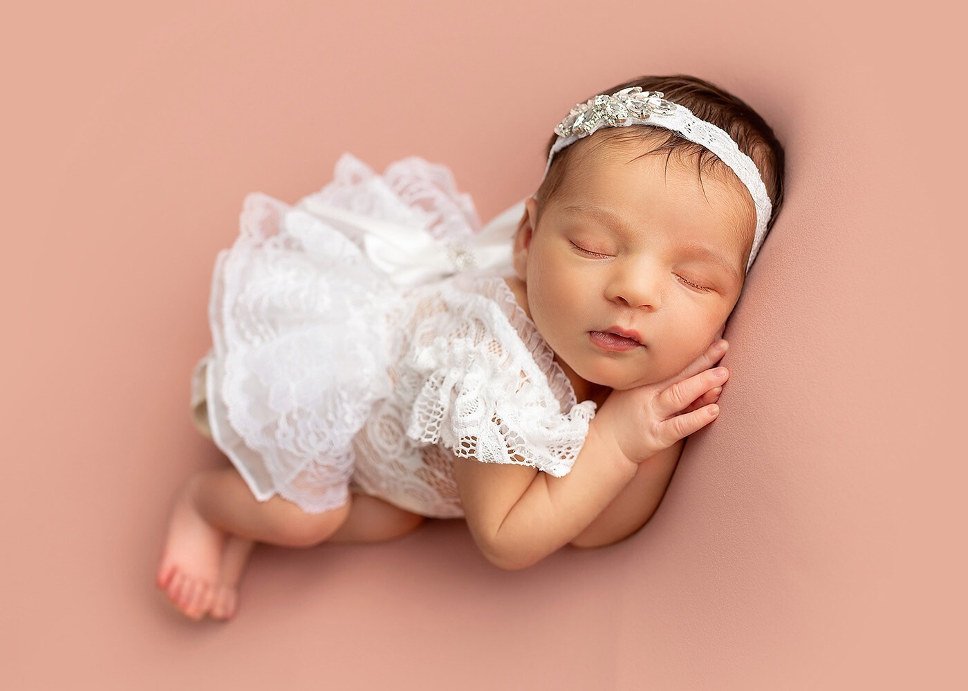 Newborn Photography and Family in NJ Sleeping newborn baby girl wearing white lace dress laying on pink posing fabric at Mount Olive NJ studio taken by Silveira's Touch Photography