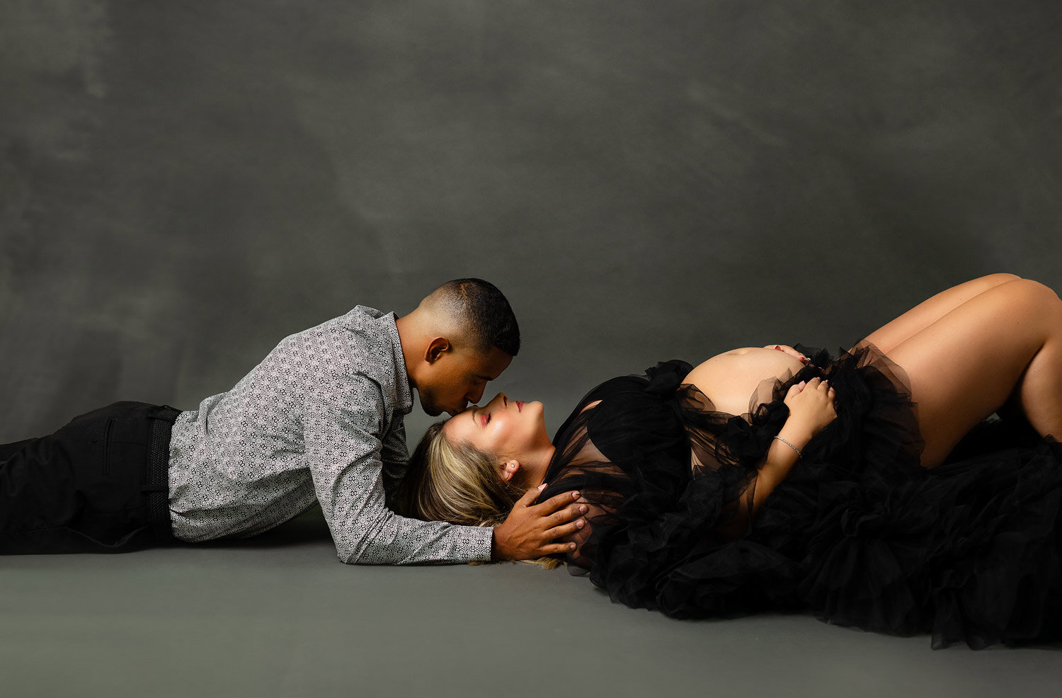 couples maternity session in studio couples maternity session in studio of dad kissing mom forehead wearing black gown