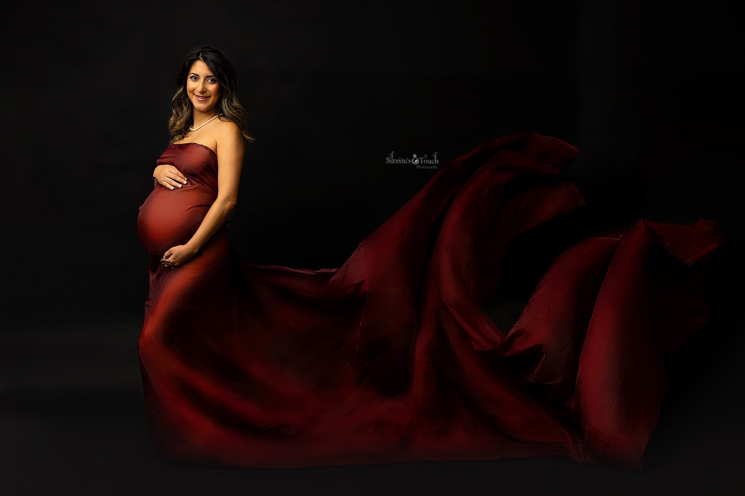 Pregnant mom wearing a flowing fabric pin red taken in Mount Olive NJ Photo studio