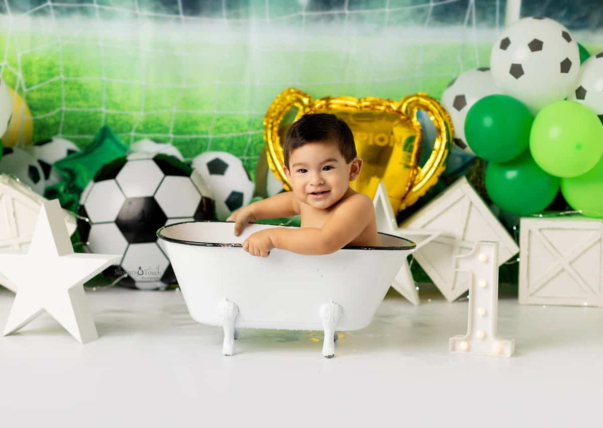 Baby smiling in tiny bathtub after a messy cake smash during the portrait session