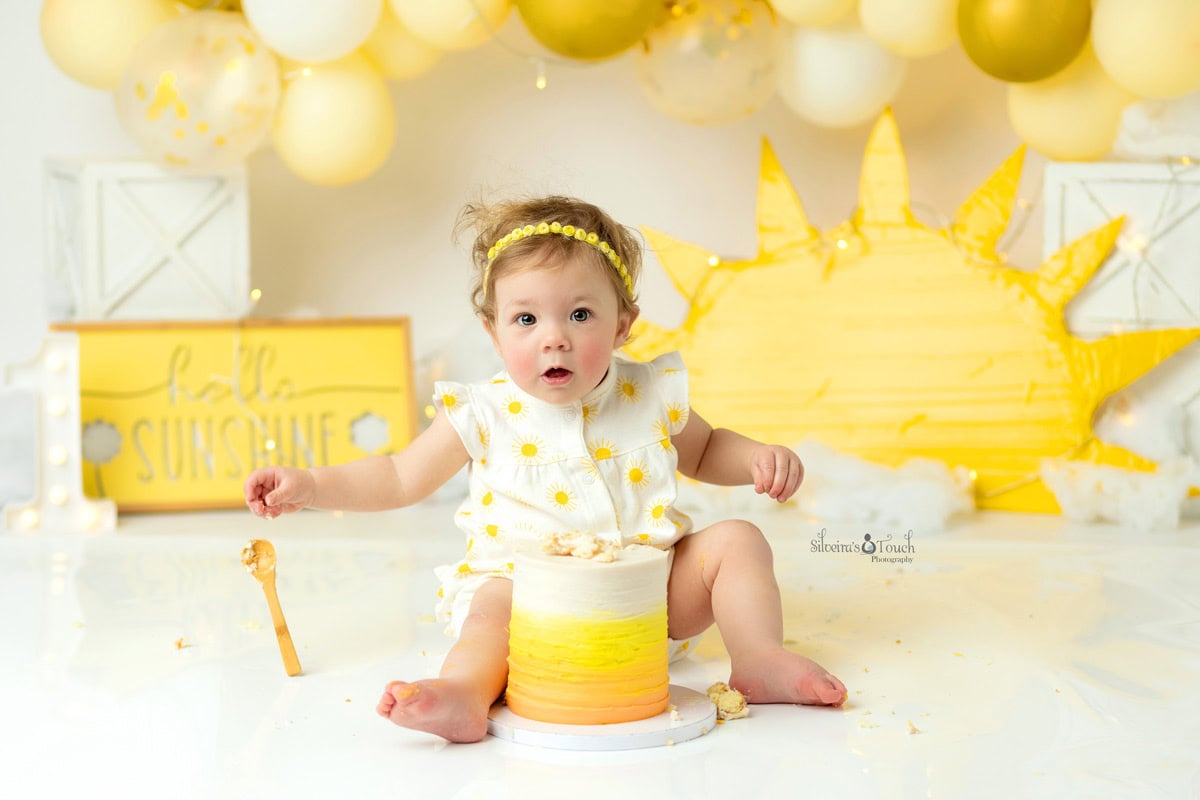 first birthday photoshoot sunshine theme nj first birthday photoshoot sunshine theme of baby holding spoon to eat her cake
