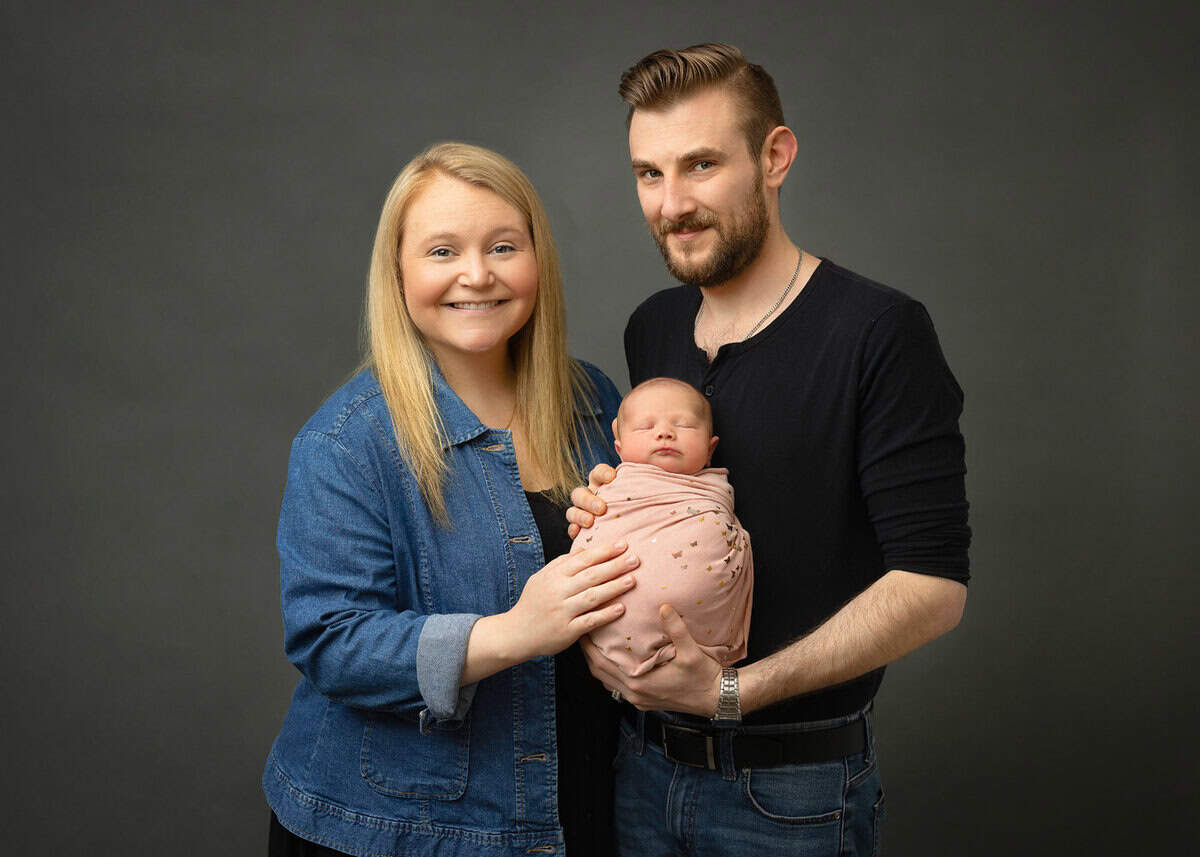 newborn family session in hackettstown nj posing with baby girl wrapped in pink blanket