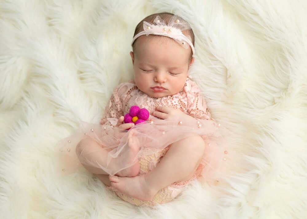 Newborn baby girl holding a felted flower captured in Mount Olive NJ by Silveira's Touch Photography