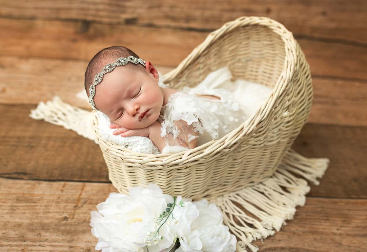 newborn baby girl in white delicate dress in wicker basket captured in Mount olive NJ by Silveira's Touch Photography