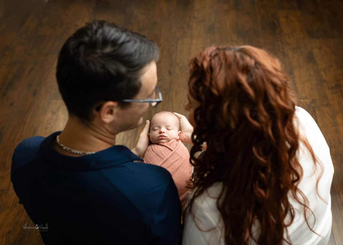 new parents holding their baby girl wrapped in pink captured in Mount olive NJ by Silveira's Touch Photography