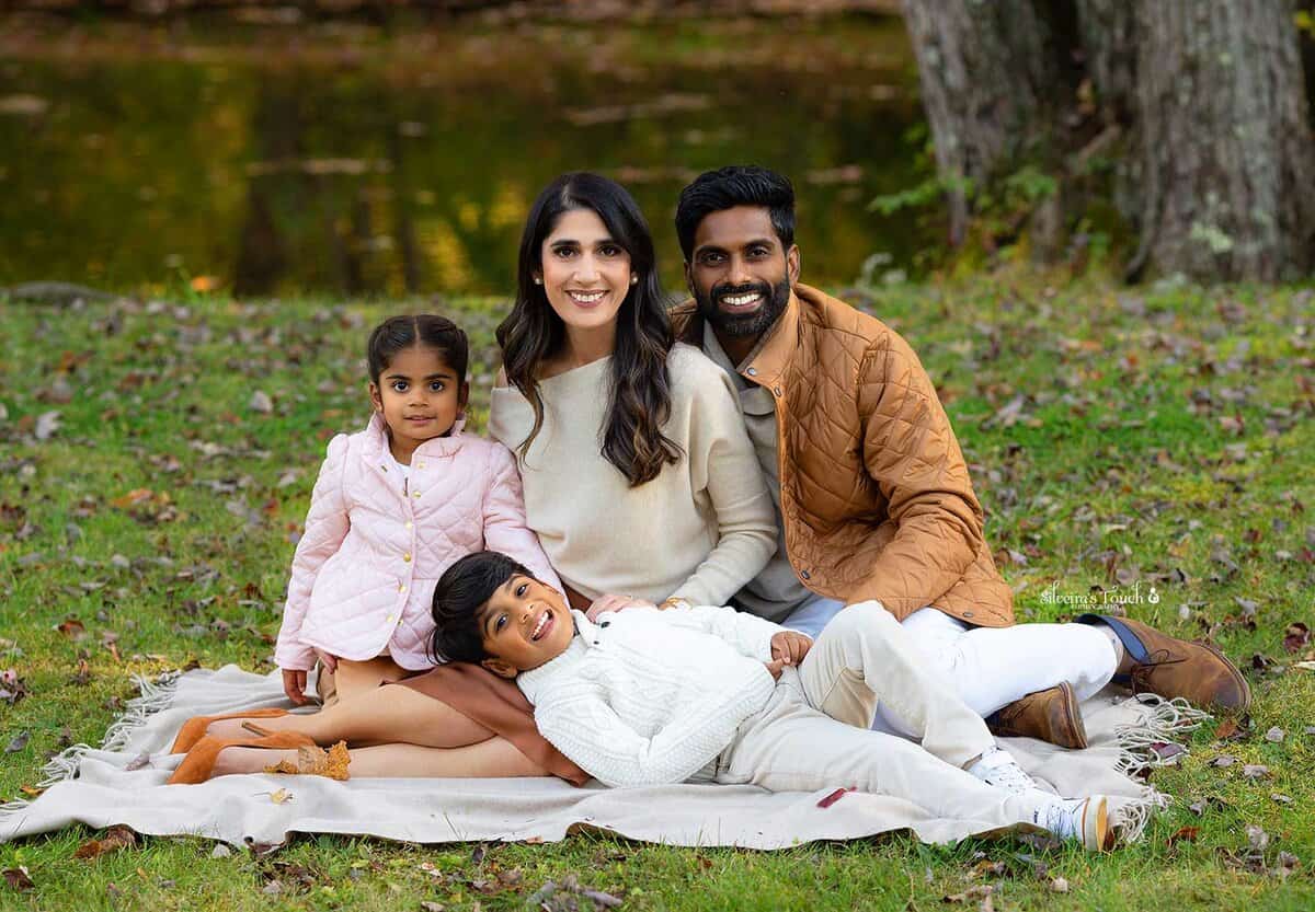 Family photography outside sitting near a pond with bright autumn color leaves in Waterloo Village NJ